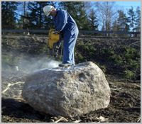 Worker breaking boulder